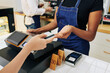 © DragonImages - Hands of customer giving credit card to cashier when paying for order in cafe