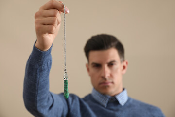 Poster - Psychotherapist with pendulum on beige background. Hypnotherapy session