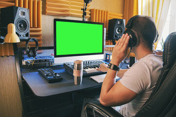 Poster - A man produce electronic music in home studio using headphones and look in green screen on monitor