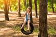© Svetlana - Happy active child girl playing on swing wheel in forest on sunny summer day. Preschool child having fun and swinging on a tire