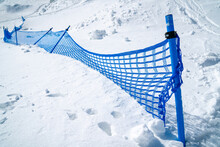 Blue Net Fence In Snow Mountain On Sunny Day.