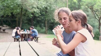 Wall Mural - Two funny sisters singing and enjoying in a picnic area