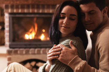 Happy couple resting near fireplace indoors. Winter vacation