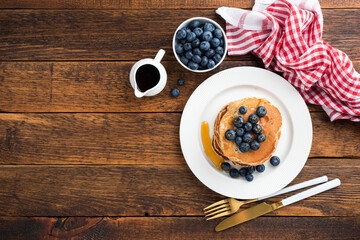 Wall Mural - Pancakes with blueberries and maple syrup on wooden table background. Table top view, copy space