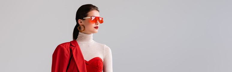 Wall Mural - panoramic shot of elegant girl in red sunglasses looking away isolated on grey