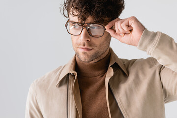 Wall Mural - handsome, stylish man touching eyeglasses while looking away isolated on grey
