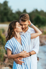 beautiful woman smiling and hugging bearded man outside