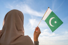 Silhouette Of Muslim Woman In Head Scarf With Pakistan Flag At Blue Sunset Sky. Concept Of Freedom