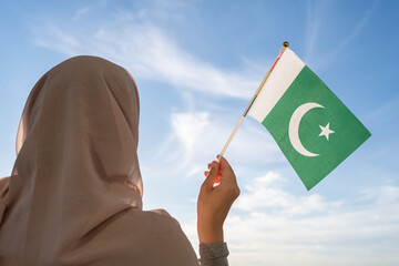 Canvas Print - Silhouette of muslim woman in head scarf with Pakistan flag at blue sunset sky. Concept of freedom