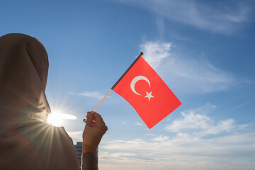 Canvas Print - Silhouette of muslim woman in head scarf with Turkish flag at blue sunset sky. Concept of freedom