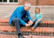 Mature Man Tickling Foot Of Toddler Girl While Cleaning Shoes