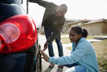 Father And Teenage Daughter Looking At Car Tire