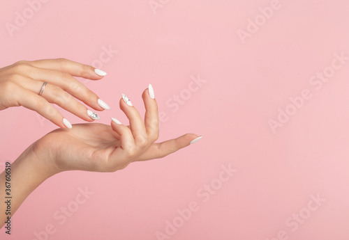 Fotografía Hands of a beautiful well-groomed woman with feminine nails on a pink background