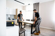 © Svitlana - Moving made simple. Full length shot of two contractor employees, young and aged repairmen in uniform moving personal belongings, table in the kitchen. Service concept