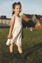 Wall Mural - beautiful little girl in a white dress on the lawn in summer
