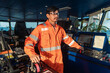© Igor Kardasov - Filipino deck Officer on bridge of vessel or ship wearing coverall during navigaton watch at sea . He is maneuvering with cpp thrusters propulsion
