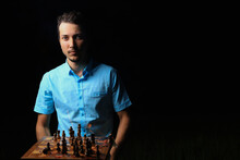 White Caucasian Young Man Or Adult Guy And A Burning Chessboard. Dark Low Key, Black Background, Selective Focus