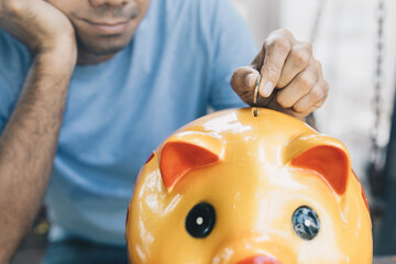 Wall Mural - Young asian man putting coin to piggy bank, Money saving concept