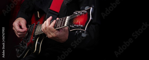Cuadros en Lienzo Guitarist hands and guitar on a black background close up