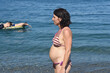  pregnant woman standing on the beach,look side