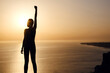 © YURII Seleznov - silhouette of woman with raised hands on the beach at sunset