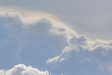 Wall Mural - white cloud and irisation cloud effect on grey sky. rainbow colours appearing on clouds.