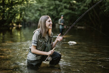 Young Adult Woman Is Fishing Alone On Fast Mountain River. Active People And Sport Fly Fishing Concept.