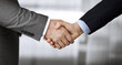 © rogerphoto - Business people in office suits standing and shaking hands, close-up. Business communication concept. Handshake and marketing
