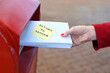 Woman sending return to sander letters in envelope in red mail box