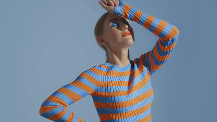 young woman with colorful makeup makes vogueing dance in studio portrait