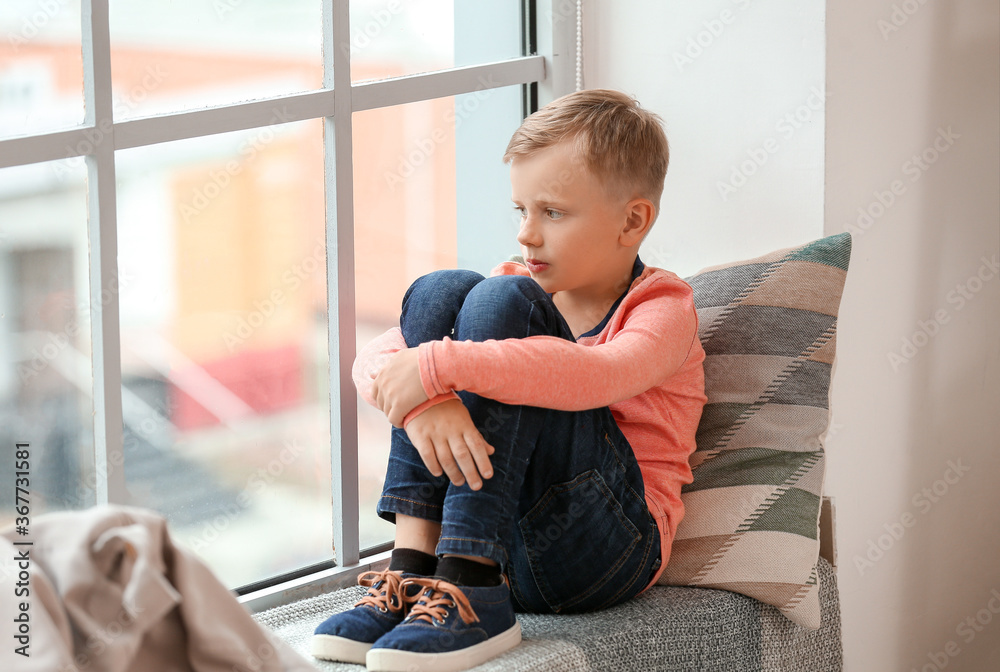 Little boy with autistic disorder sitting near window at home