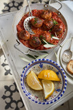 Fototapeta  - Dish of spicy meatballs with fresh lemon wedges