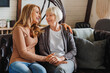 © InsideCreativeHouse - Senior mother with adult daughter hugging each other on sofa in living room