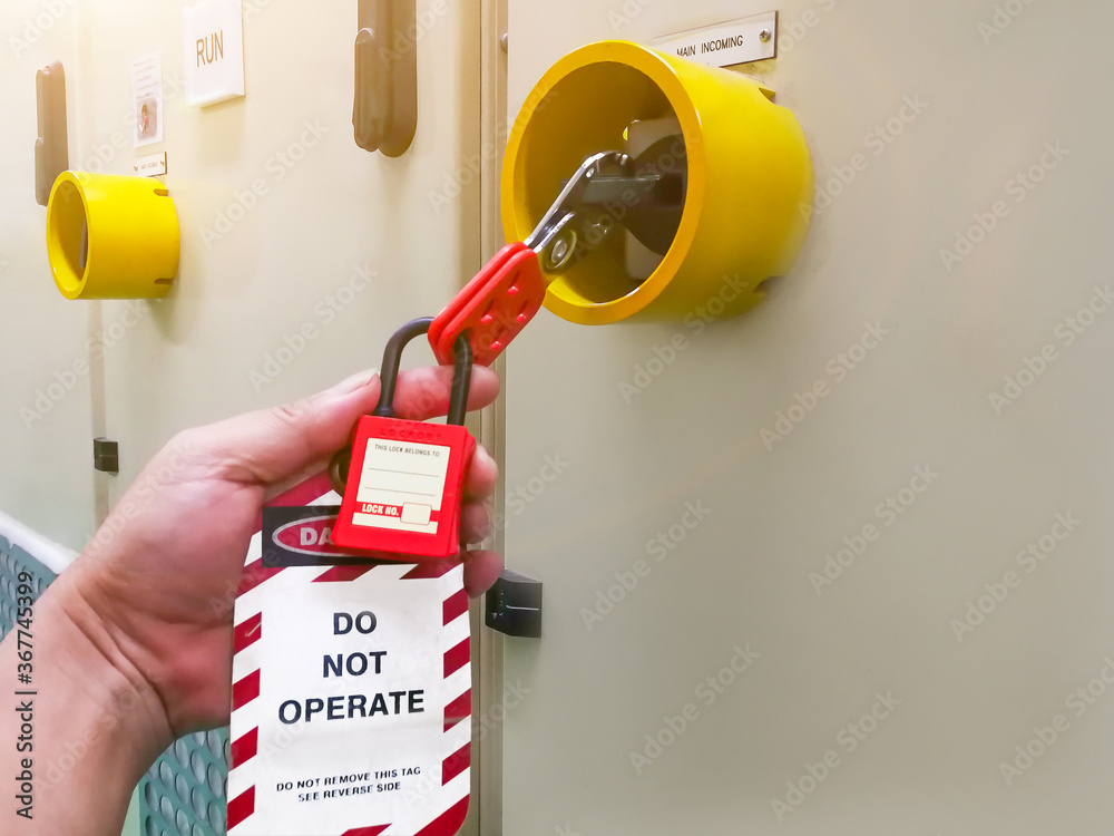 Hand holding red key lock and tag for process cut off electrical,the toggle tags number for electrical log out tag out - obrazy, fototapety, plakaty 