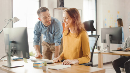 Poster - Female Specialist Works on Desktop Computer, Project Manager Stands Beside and gives Advice on Optimizing Workflow for Customer Experience Management. Modern Office with Diverse Team of Professionals