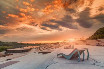 Wall Mural - People relax and walk in the coastal city Park and enjoy the view of the sunset and the river.