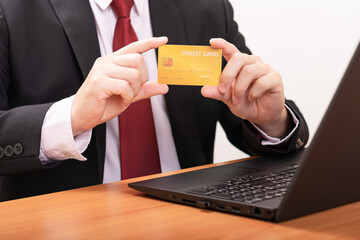 Close-up Of A Business Man's Two Hand Holding Gold Credit Card At Front Of Laptop. Business concept and Online concept