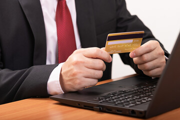 Close-up Of A Man's Two Hand Holding Credit Card on Front Of Laptop