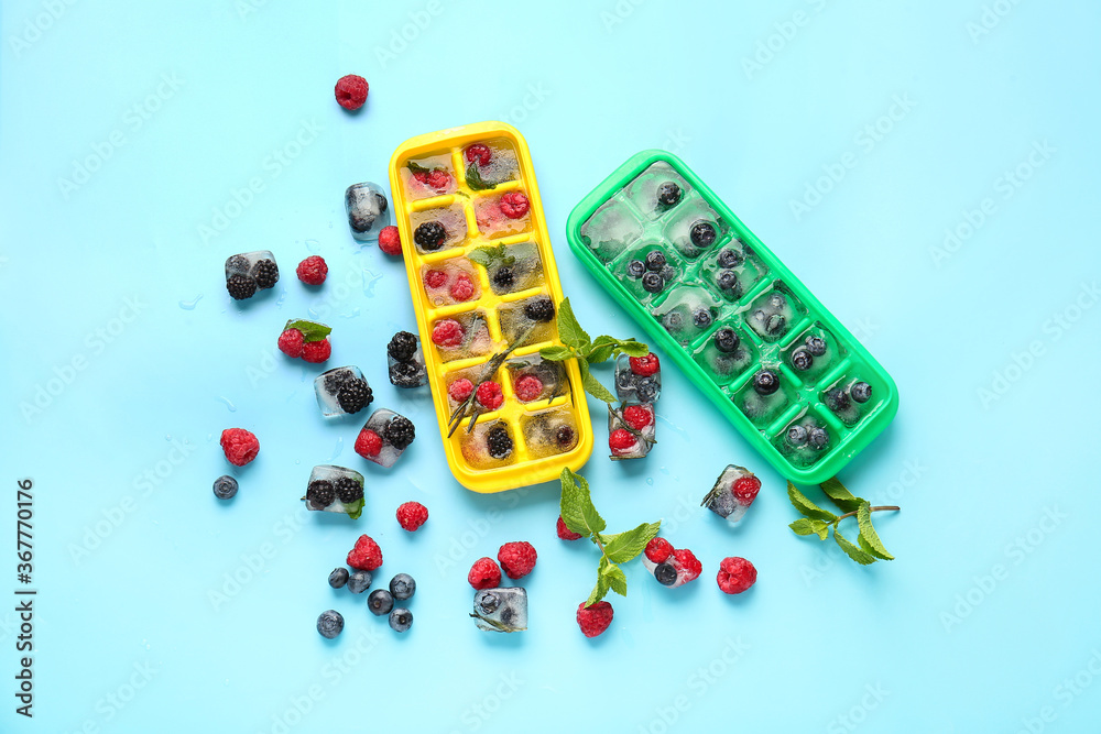 Trays with berries in ice on color background