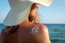 An Young Woman With Applied Sun Shape Of Sunscreen Or Sun Tanning Lotion On A Shoulder To Take Care Of Her Skin On A Seaside Beach During Holidays Vacation.