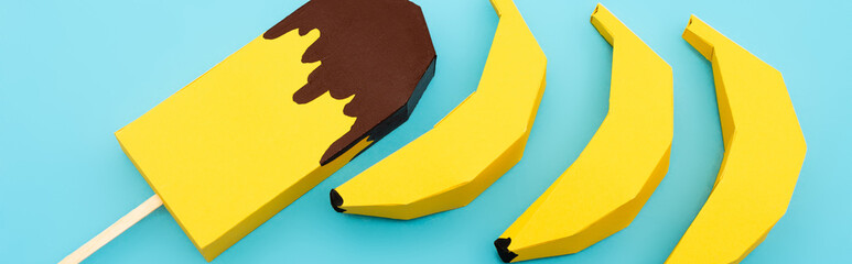 Wall Mural - top view of paper yellow bananas and ice cream on blue background, panoramic shot