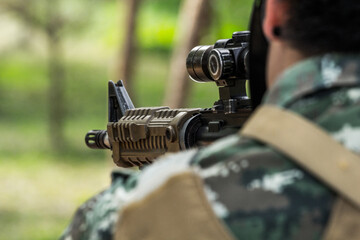 Military shooter with his precising assault rifle aiming and shooting target in the range