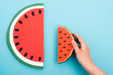 Sticker - partial view of female hand with paper watermelon slices on blue background