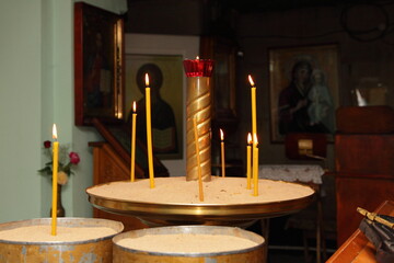 Church ritual candles in sand candlesticks on Icons background, religious equipment of Christianity