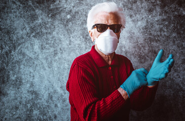 Wall Mural - Old grandmother protect herself from coronavirus infection with medical gloves and respirator mask