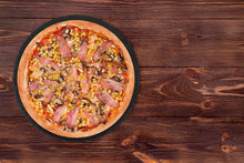 Delicious Pizza With Chicken Breast, Corn, Bacon And Mushrooms, On A Round Slate Plate Which Is On Wooden Table, Top View And Copy Space