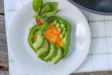 Healthy Breakfast of fried eggs in pepper rings with avocado and green peas