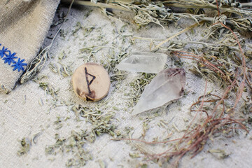 Scandinavian wooden rune Thurisaz, Thurs on a rough linen cloth with amethyst crystalline, rock crystal and dried wormwood