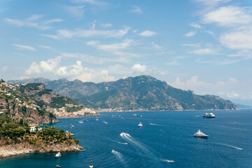 Wall Mural - View from Conca dei Marini on Amalfi bay, Luxury boats traffic, ocean liner, fishing boats, tourist season. watercraft. Mountains and houses, buildings. Summer day. Amalfitana Italy