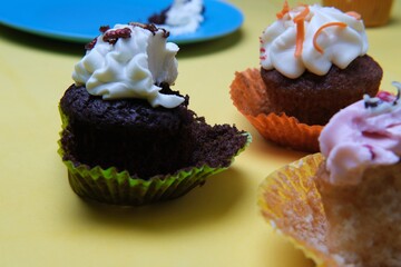 Sticker - Closeup shot of cute cupcakes with a bitten chocolate one